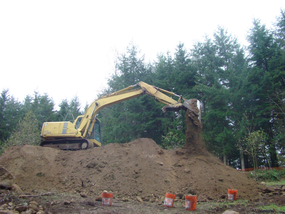 Excavator on mound dropping soil