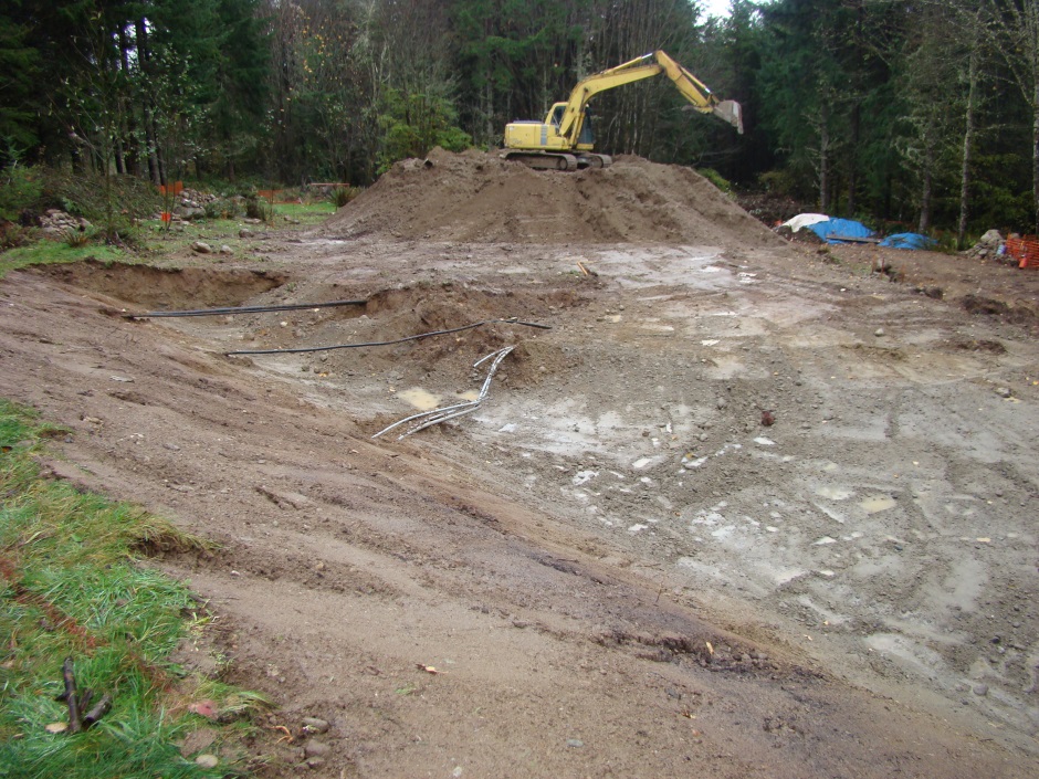 Excavator on mound showing pipes