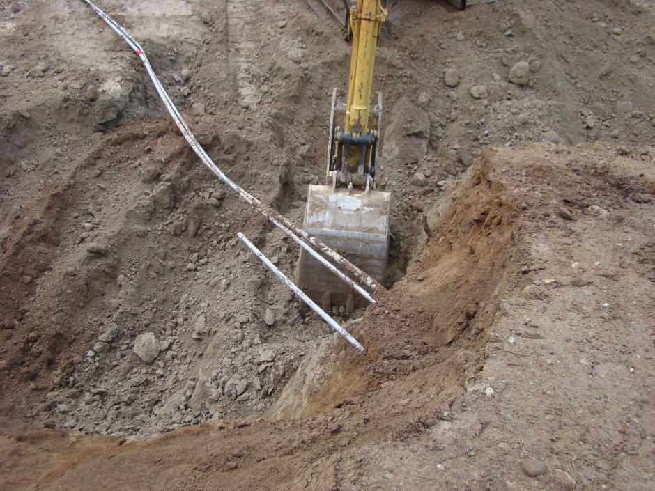 Excavator digging under conduit